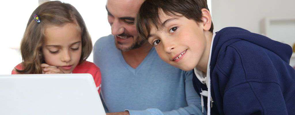 Father helping son and daughter with homework on a laptop computer